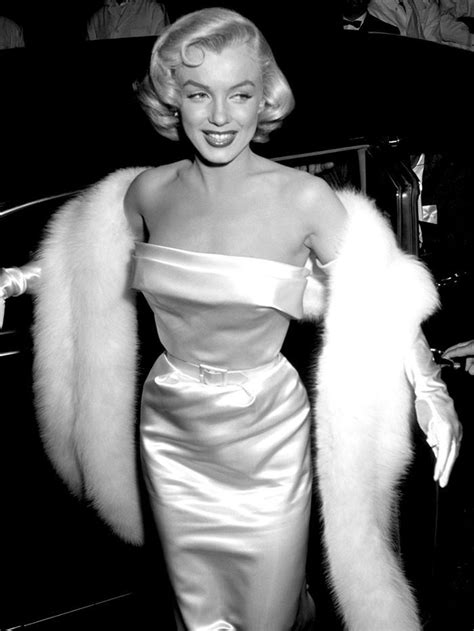 a black and white photo of a woman in a dress with fur stole around her shoulders