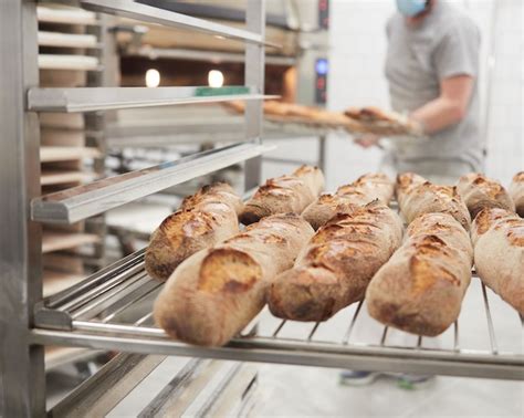 Premium Photo Baker At Work In The Bakery Placing Freshly Baked