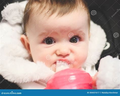 Portrait Of One Beautiful Baby Girl Drinking Milk From A Bottle Stock