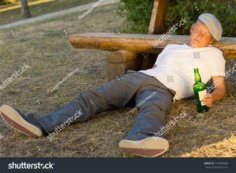 Drunk Man Fallen Asleep On The Ground Leaning His Head On A Bench