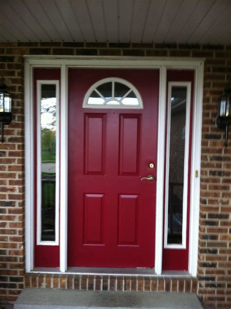 A Red Front Door With Two Sidelights On The Brick Wall And Concrete