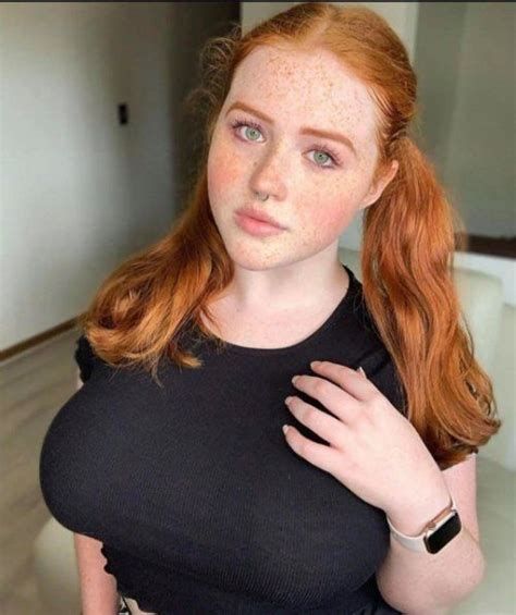 A Woman With Freckles On Her Face Is Posing For The Camera And Has Red Hair
