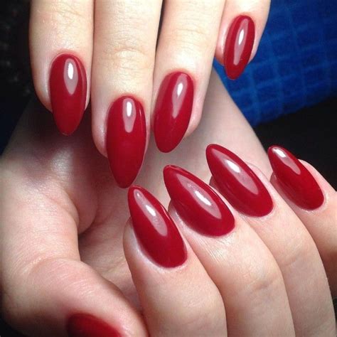 deep red glossy nail polish, on almond shaped nails, worn by two pale