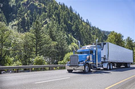 Powerful Blue Big Rig Long Haul Semi Truck Transporting Frozen Cargo In