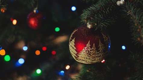 A Christmas Ornament Hanging From The Top Of A Tree With Lights In The