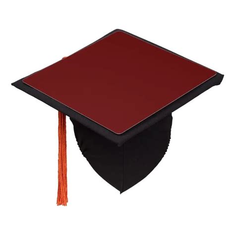 A Red And Black Graduation Cap With An Orange Tassel