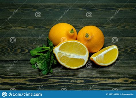 Two Whole Bright Yellow Lemons And Two Halves Of Lemon With Mint Leaves