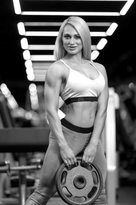 Fitness Blonde Woman Is Standing With Dumbbells In The Gym Stock Image