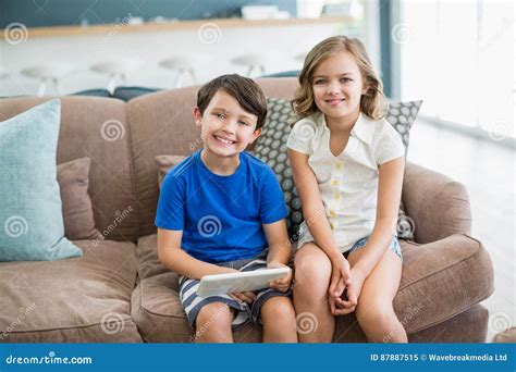 siblings using digital tablet on sofa in living room at home stock image image of bonding