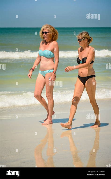 Zwei ältere Frauen im mittlere alte in Bikinis schlendern am Strand