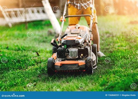 Industrial Gardener Working With Lawnmower And Cutting Grass In The