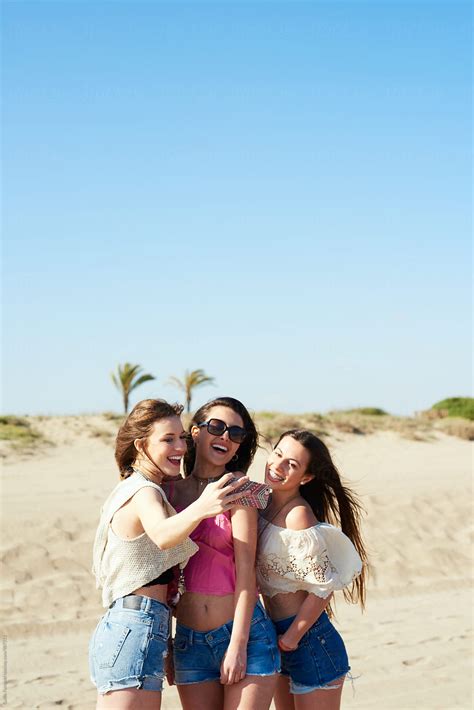 Three Girlfriends Taking Selfie On Beach By Stocksy Contributor