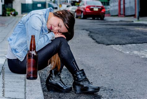 Beautiful Young Drunk Woman Sitting In A Sidewalk With Bottle Of Beer