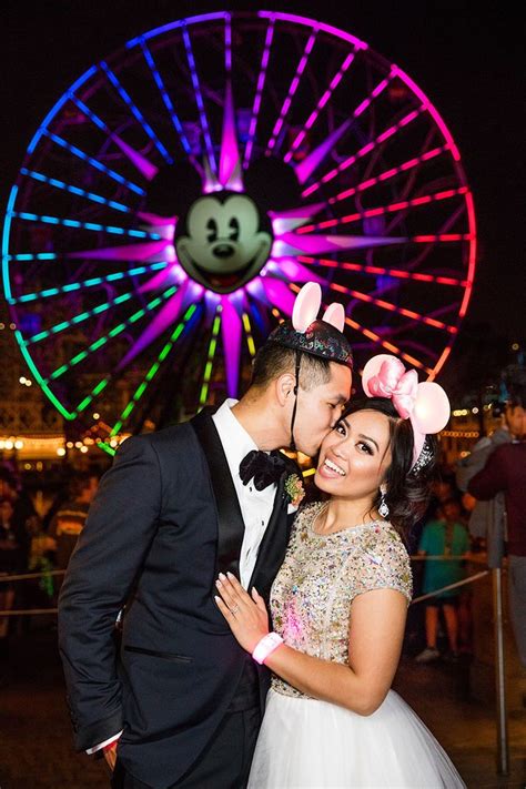 A Bride And Groom Pose For A Photo In Front Of A Ferris Wheel At Night