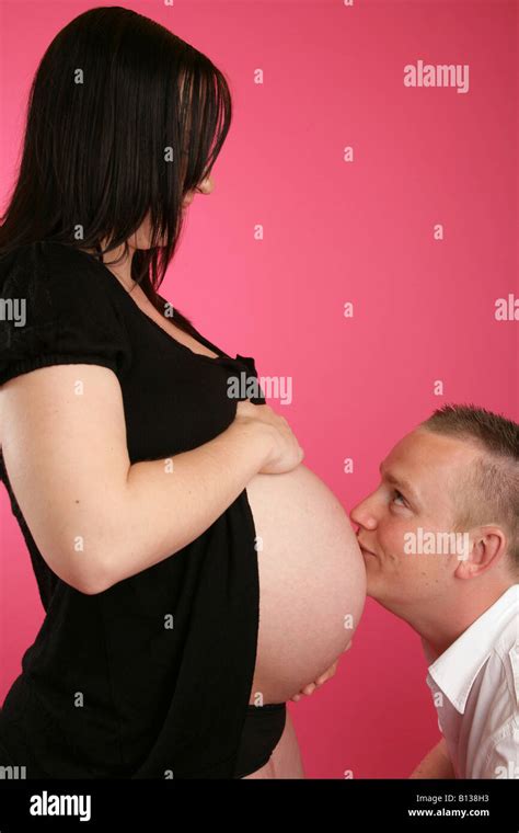 A Husband Kissing His Wifes Pregnant Exposed Tummy Stock Photo Alamy