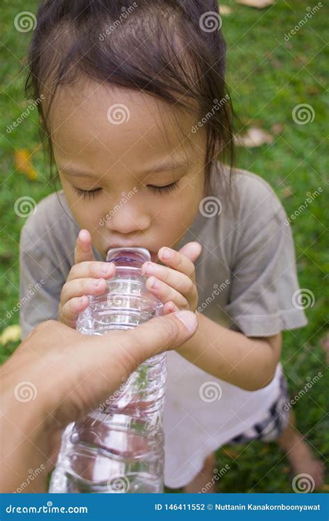 Little Children Drinking Water From Bottle In Green Park Stock Photo
