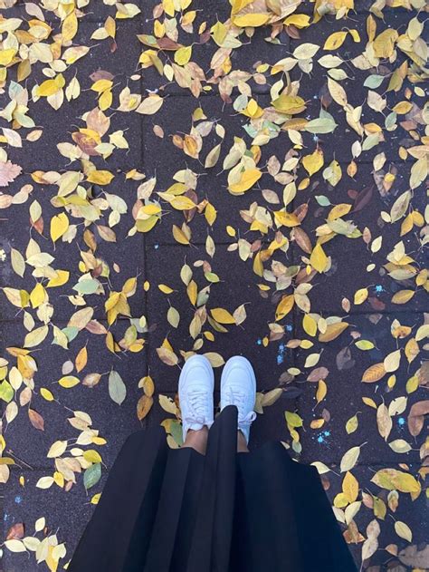 A Person Standing In Front Of A Leaf Covered Floor With Their Feet Up