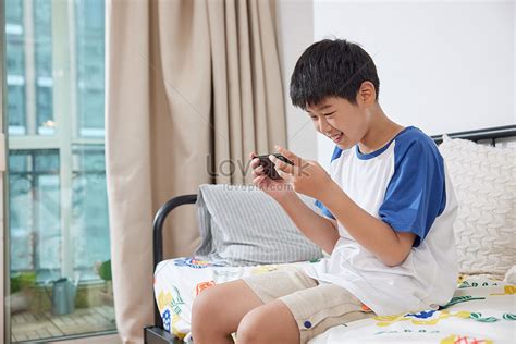 Boy Excitedly Playing With Mobile Phone On Sofa Picture And Hd Photos