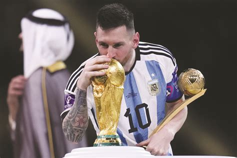 lionel messi kisses the fifa world cup trophy as he holds the golden ball award for best player