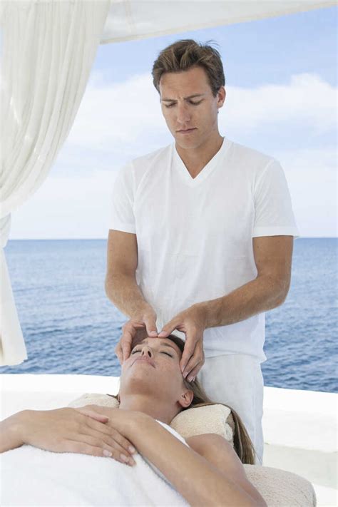 Male Masseur Giving Young Woman A Head Massage At Beach Resort Majorca