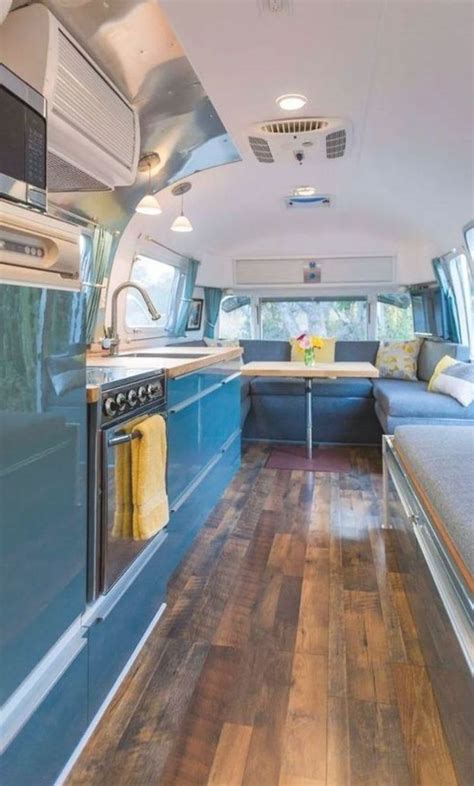 The Interior Of A Camper Van With Wood Floors And Blue Cabinets