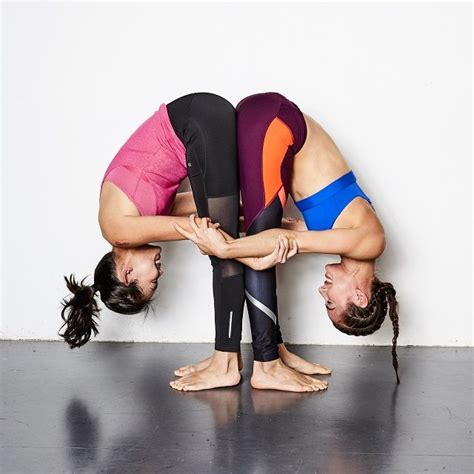 two women doing handstands on the floor in front of a white wall
