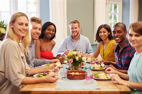 Friends At Home Sitting Around Table For Dinner Party Stock Photo