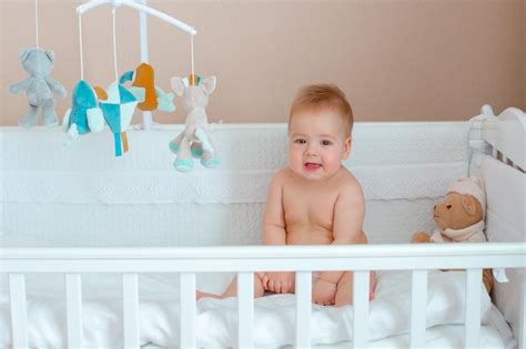 Premium Photo A Baby Boy In A Diaper Is Sitting In A Crib In The Bedroom