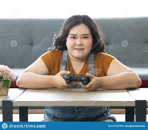 Portrait Of Chubby Asian Woman Sitting And Holding A Joystick Looking