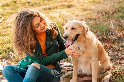 Young Curly Woman With Her Dog Golden Retriever Embracing Outdoors