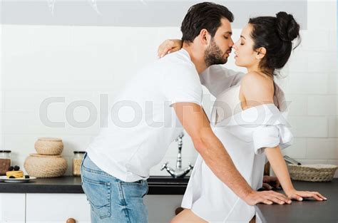 side view of man kissing sensual woman in bra and shirt in kitchen stock image colourbox