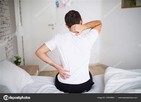 Man Suffering From Back Pain At Home In The Bedroom Uncomfortable