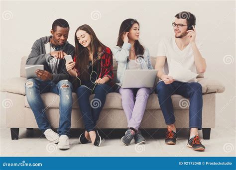 Diverse Students Using Gadgets Sit On Sofa Stock Photo Image Of