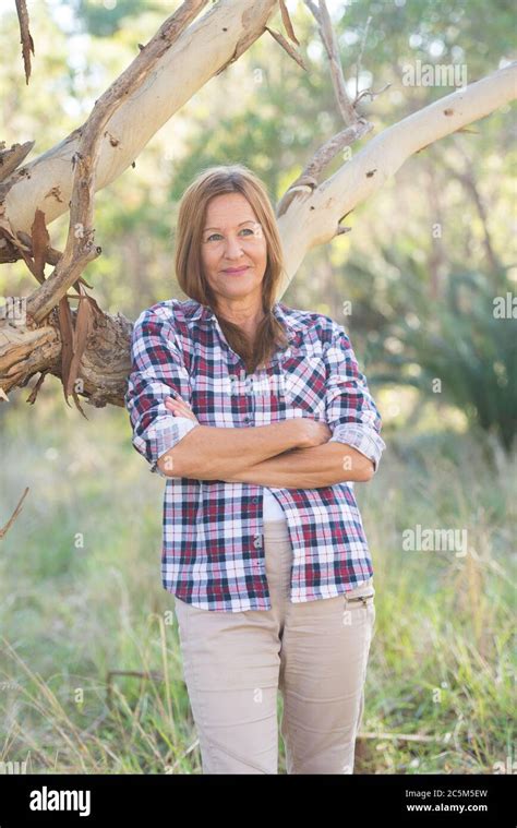 portrait attractive mature woman in rural country wearing plaid shirt posing relaxed with