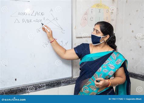 Female Teacher Wearing Mask And Saree Teach Math On Whiteboard In