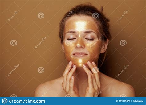 Modern Woman With Golden Mask Making Facial Self Massage Stock Image
