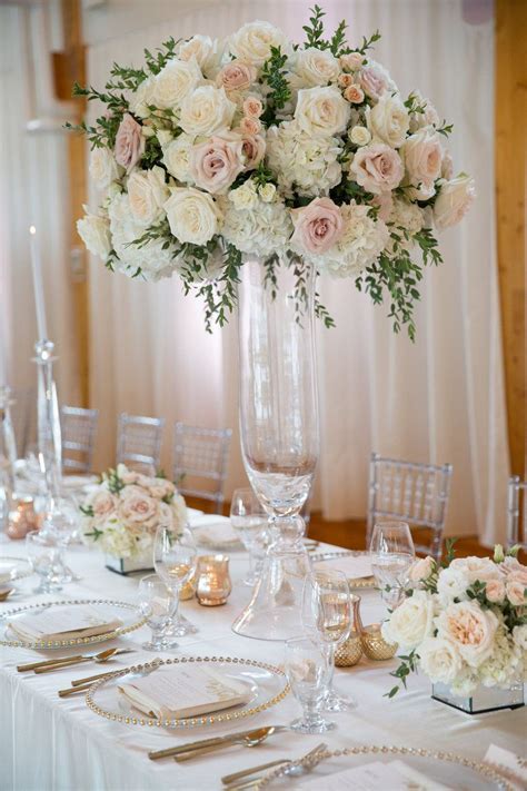 a tall vase filled with white flowers on top of a table covered in silverware