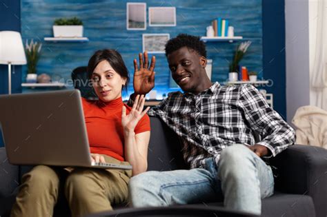 Happy Interracial Couple Waving At Computer Screen Stock Photo By Dcstudio