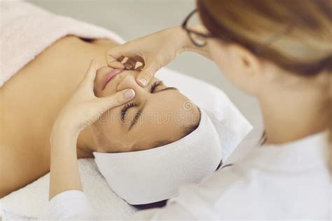 Female Beautician Doing Facial Massage For Client Lying In Beauty Center Or Spa Stock Image