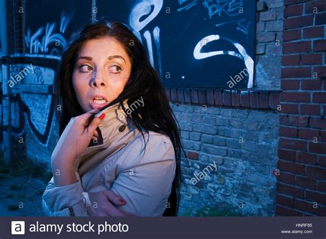 Young Black Haired Woman On A Brick Wall Sprayed With Graffiti In The