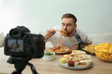 Food Blogger Recording Eating Show On Camera Against Light Background