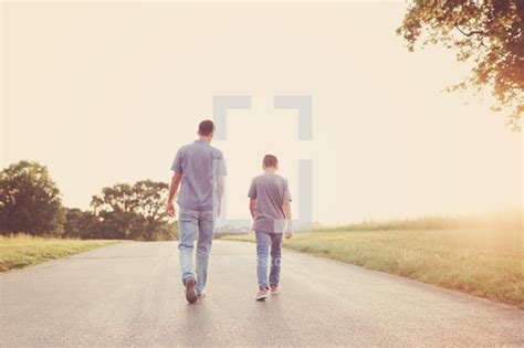 A Father And Son Walking Down A Rural Road — Photo — Lightstock