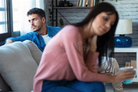 Angry Young Couple Sitting On Couch Together And Looking To Opposite