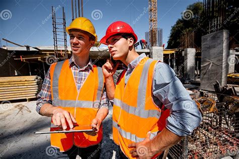Structural Engineer And Architect Dressed In Orange Work Vests And Hard