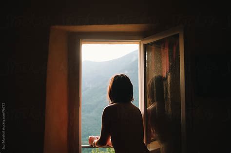 Woman Standing At An Open Window Watching The Sunrise By Suzi Marshall