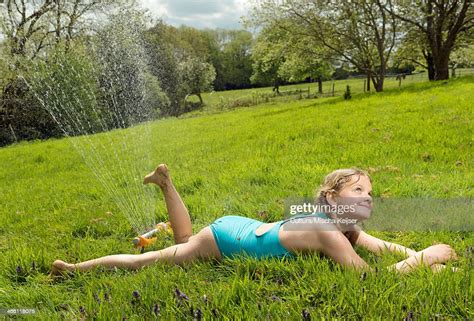 Young Girl Lying Under Garden Sprinkler In Field Photo Getty Images