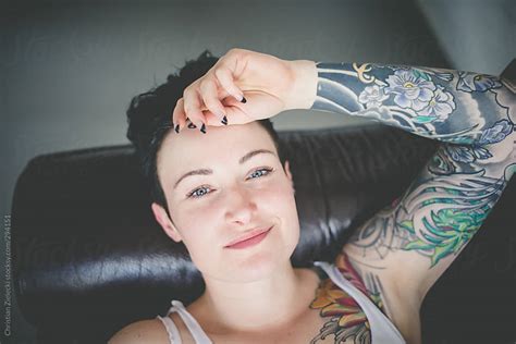 Tattooed Girl With Short Black Hair Lying On A Couch By Chris Zielecki Stocksy United