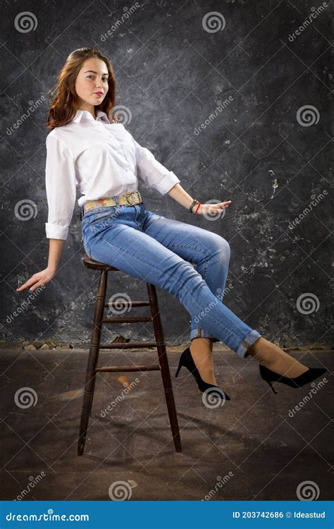 Beautiful Teen Girl Dressed In Blue Jeans And White Shirt Sitting On