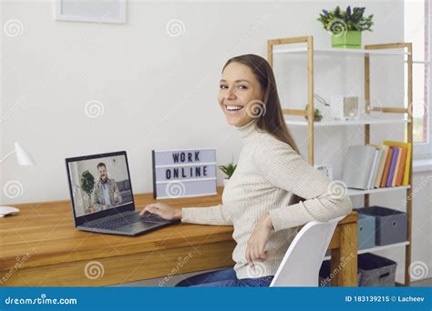 Online Work At Home A Woman Works At A Table In Using A Laptop She
