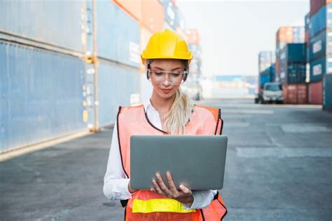 foreman woman worker working checking at container cargo harbor holding laptop computer to